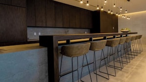 A modern kitchen with a long counter, bar stools, and pendant lighting. - Experience Design District, Pool, Gym and Parking (Miami)