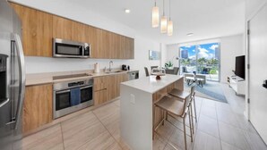 Een moderne keuken met houten kastjes, roestvrijstalen apparatuur en een centraal eiland met barkrukken.