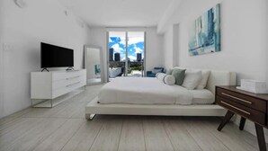 Een moderne slaapkamer met een bed, een televisie, een dressoir en een schilderij aan de muur.
