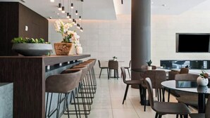A modern kitchen with a bar area, seating, and a large TV. - Modern Design District Condo, Balcony, Pool, Gym (Miami)
