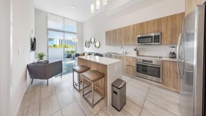 A modern kitchen with a central island, stainless steel appliances, and a view to the outside. - Relax with Pool, Gym, Balcony in Design District (Miami)