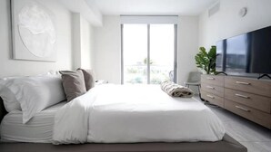 Ein modernes Schlafzimmer mit einem großen Bett, einem Fernseher und einer Pflanze.