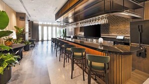Eine moderne Bar mit einer langen Theke, Barhocker und einer Ziegelwand im Hintergrund.