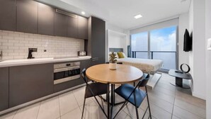 A modern kitchen with grey cabinets, a white countertop, and a round dining table with blue chairs. - Penthouse Studio in heart of Miami w pool & gym (Miami)