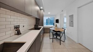 A modern kitchen with a long countertop, built-in oven, and a dining area with a table and chairs. - Penthouse Studio in heart of Miami w pool & gym (Miami)