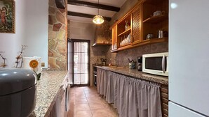 A narrow kitchen with a stone wall, a microwave, and a sink. - Awesome home in El Chorro, Alora (El Chorro, Alora)