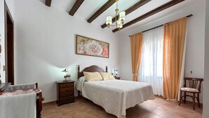 A bedroom with a bed, nightstands, a chair, a painting, and a chandelier. - Awesome home in El Chorro, Alora (El Chorro, Alora)