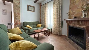 A living room with a green sofa, yellow cushions, a wooden coffee table, and a fireplace. - Awesome home in El Chorro, Alora (El Chorro, Alora)