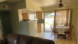 Una sala de estar con un sofá de cuero marrón y una zona de comedor con una mesa y sillas.