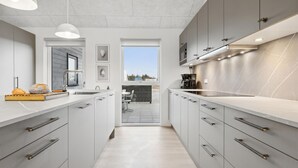 Una cocina moderna con armarios blancos, un ventanal y vistas al exterior.