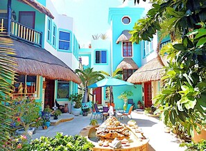 A courtyard with a fountain, potted plants, and outdoor seating. - Casa Gatos (Akumal)
