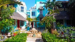 A tropical resort with colorful buildings, a central fountain, and lush greenery.