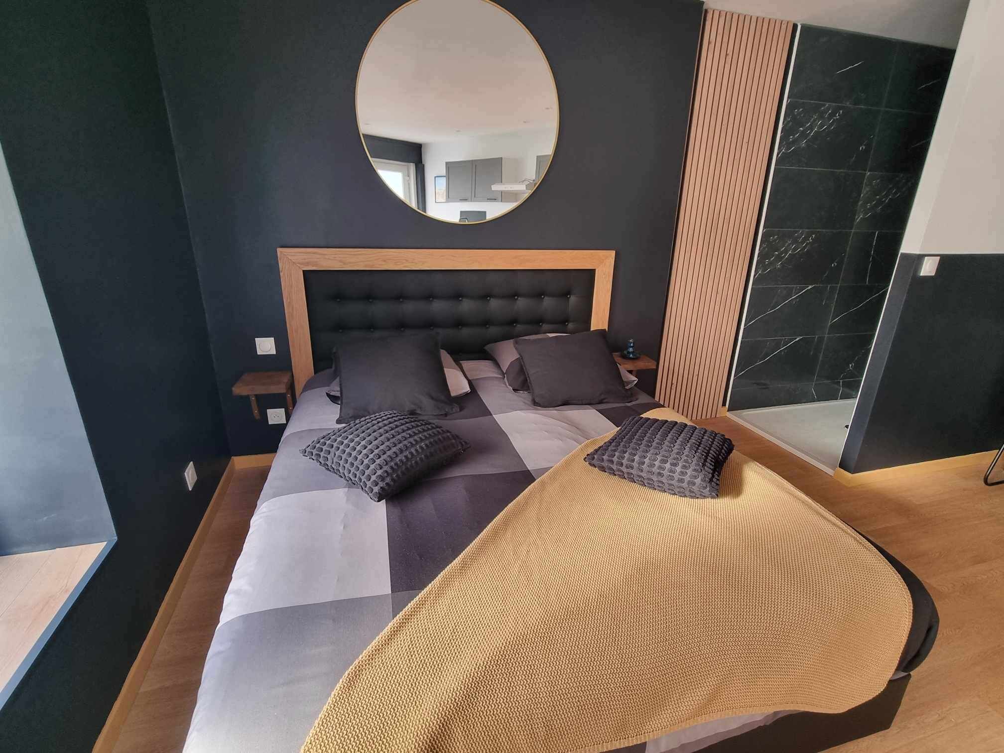 Ein modernes Schlafzimmer mit einem großen Bett, einem Kopfteil und einem runden Spiegel an der Wand.