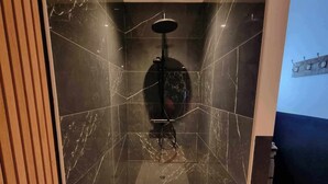 A modern shower with a glass enclosure, marble walls, and a wooden floor. - The black tendance, maxi studio hyper center, 1km from train station, tourism/business (Calais)