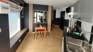 A modern kitchen with a dining area, including a table with chairs, a stove, and a sink. - The black tendance, maxi studio hyper center, 1km from train station, tourism/business (Calais)