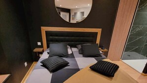 A modern bedroom with a large bed, a round mirror, and a view of the outside. - The black tendance, maxi studio hyper center, 1km from train station, tourism/business (Calais)