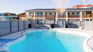 A swimming pool with a wooden deck and a no diving sign.