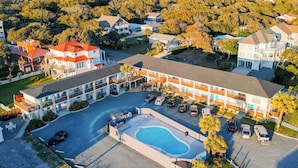 An aerial view of a motel with multiple buildings, a swimming pool, and a parking area.