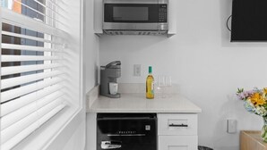 Una cocina moderna con armarios blancos, microondas integrado, cafetera y lavavajillas.