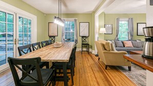 A dining area with a wooden table and chairs, a sofa, and a coffee machine.