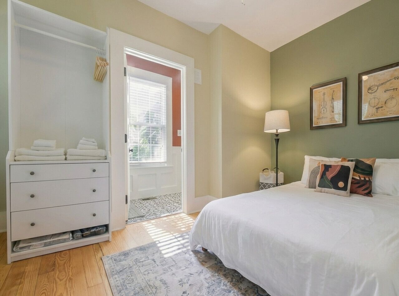 A bedroom with a bed, a wardrobe, a window, and a door.