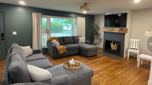 A modern living room with a grey sectional sofa, a small white chair, and a fireplace. - mi casa es TU casa (Center) (Upland)