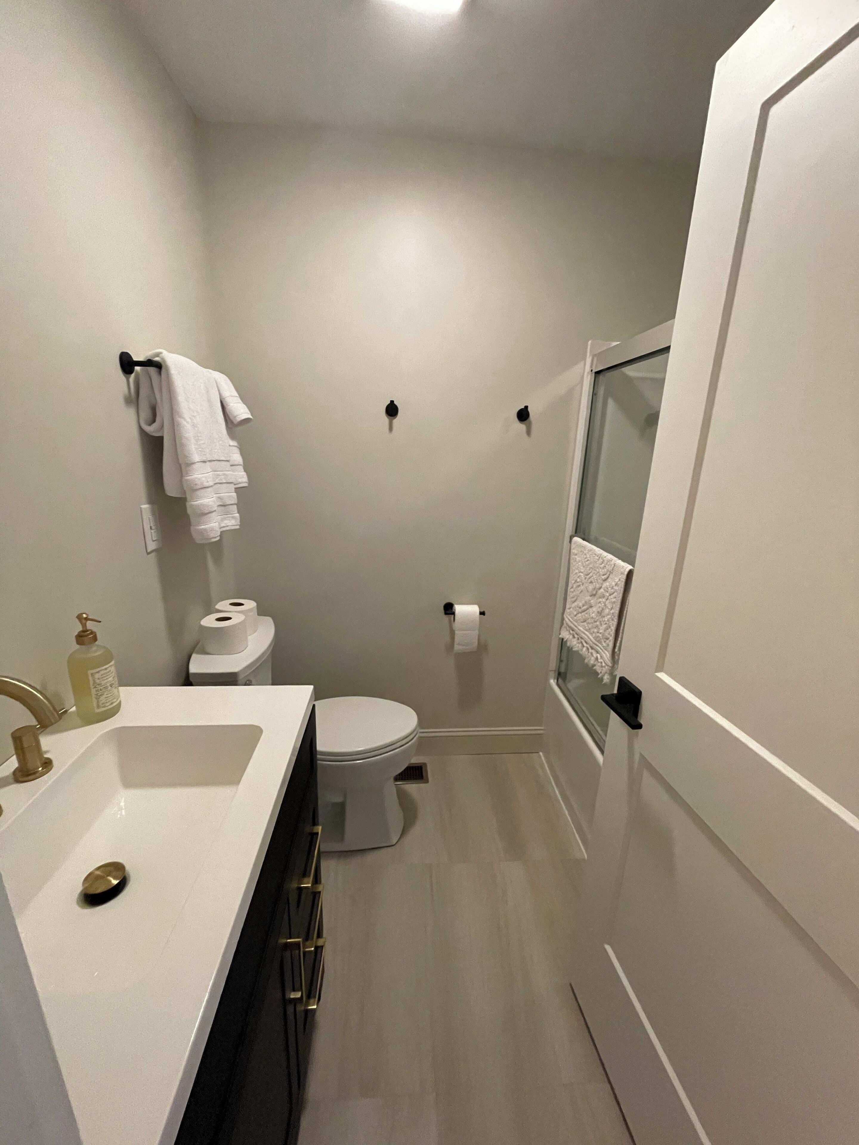 Et lille badeværelse med vask, toilet og bruseområde.