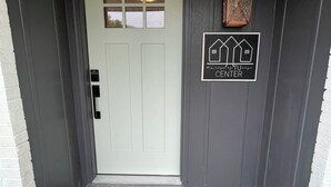 A front door with a white door, a welcome mat, and a sign indicating a center. - mi casa es TU casa (Center) (Upland)