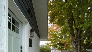 A house with a white exterior, a front door with a doormat, a pathway leading to the door, and a tree with green leaves. - mi casa es TU casa (WEST) (Upland)