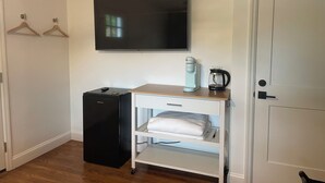 A compact room with a flat-screen TV, a small kitchenette with a coffee maker, and a white cabinet with a folded towel. - mi casa es TU casa (WEST) (Upland)