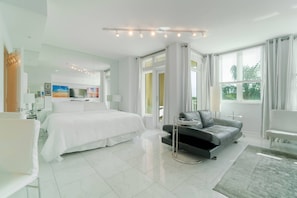 Quarto de hotel moderno com uma cama grande, um sofá, uma escrivaninha e vista para o exterior.