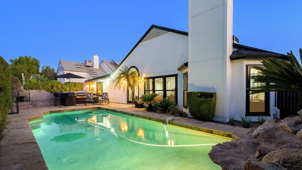 Una casa moderna con piscina, mobiliario exterior y un jardín bien cuidado.