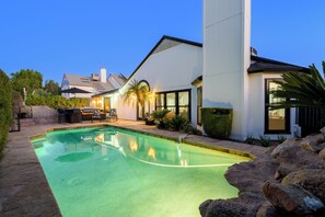 A modern house with a swimming pool, outdoor seating, and a well-maintained garden.