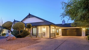 Una casa moderna con porche cubierto, garaje y jardinería bien cuidada.