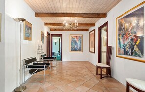 Un couloir doté d’un sol carrelé, d’un lustre et d’œuvres d’art encadrées accrochées aux murs.
