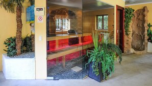 Un intérieur moderne agrémenté d’une cloison en verre, d’un banc en bois et d’un grand élément décoratif en pierre.