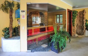 Een modern interieur met een glazen scheidingswand, een houten bank en een grote rots.