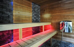 Een sauna met houten banken en een stenen muur, met een Harvig sauna-kachel.