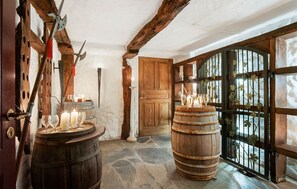 Un interior rústico con barriles de madera, piso de piedra y puerta de madera.