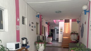 Un pasillo con piso estampado, plantas en macetas, un microondas y una escalera que lleva a otra habitación.