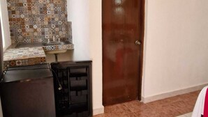 Una habitación con pared y piso de baldosas, y una puerta de madera.