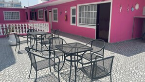 Un edificio rosa con patio empedrado, asientos al aire libre y una puerta con el número 201.