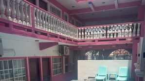 Un edificio de varios niveles con piscina, balcones y una zona cubierta con sillas.