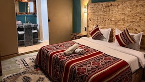 Ein Schlafzimmer mit einem großen Bett, einem Kopfteil und Blick auf ein Badezimmer.