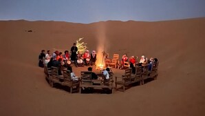 Eine Gruppe Menschen versammelt sich an einem Lagerfeuer in Wüstengebiet.
