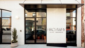 A hotel entrance with a white brick facade, large glass doors, and the name "ARCHWAY HOTEL RESIDENCE" displayed. - Archway Hotel & Residences (Philadelphia)