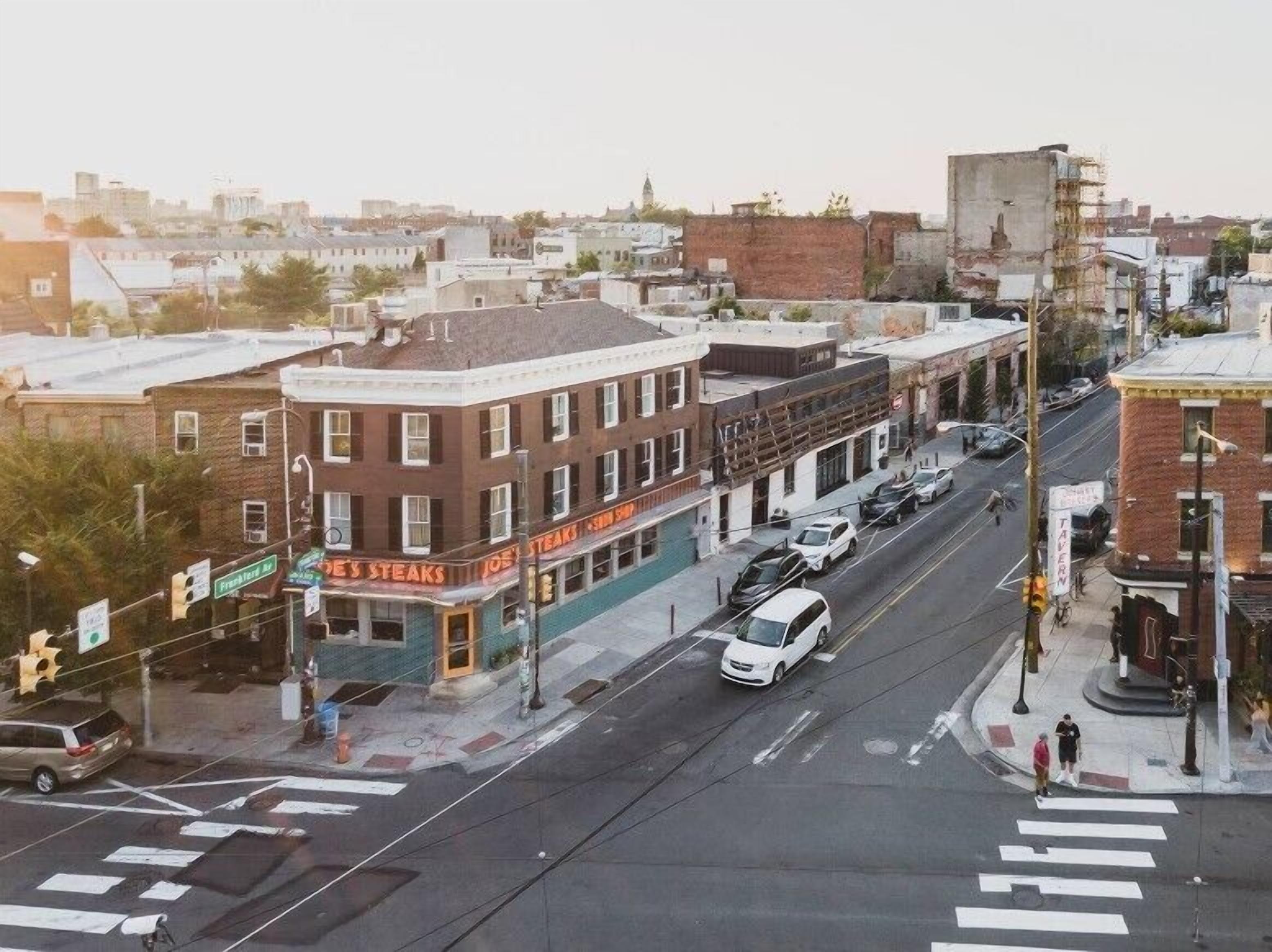 A street view of a city with a restaurant named 'Joe's Steaks' on the corner.