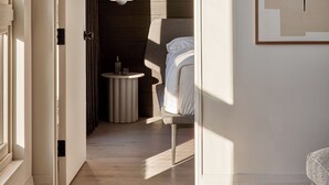 A modern interior with a hallway leading to a bedroom, a hanging light fixture, and a framed abstract artwork on the wall. - Archway Hotel & Residences (Philadelphia)