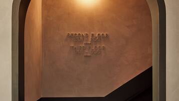 An arched doorway with a recessed light fixture and directional signage indicating room numbers for the second and third floors.