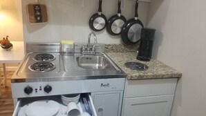 Una cucina compatta con piano cottura integrato, lavello e scolapiatti.